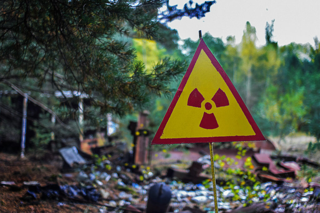 yellow-red triangular radiation sign against the background of radioactive waste warns the workers of the landfill about the danger of infection by radiation