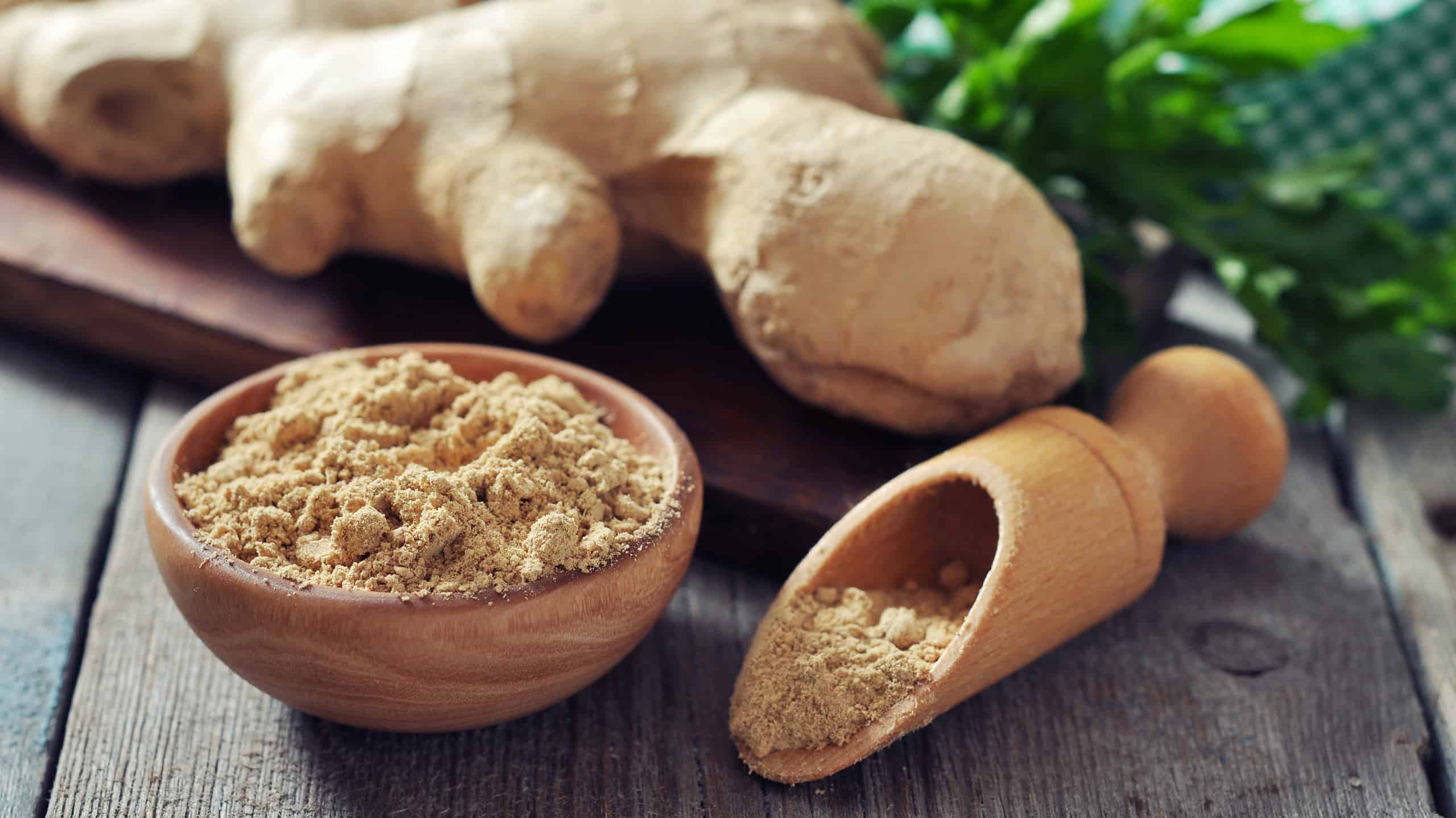 Fresh ginger root and ground ginger spice on wooden background
