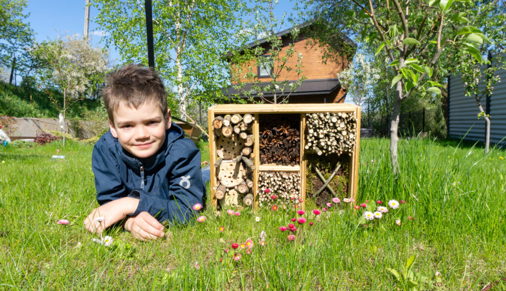Cute boy made an insect diy house or a dormitory for bugs and beetles to protect the environment in the garden. 