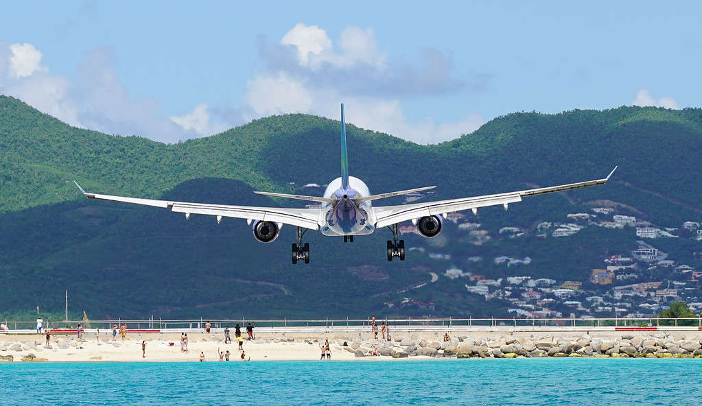 Airplane flying over people during landing at Maho Beach in Saint Maarten at Princess Juliana airport.