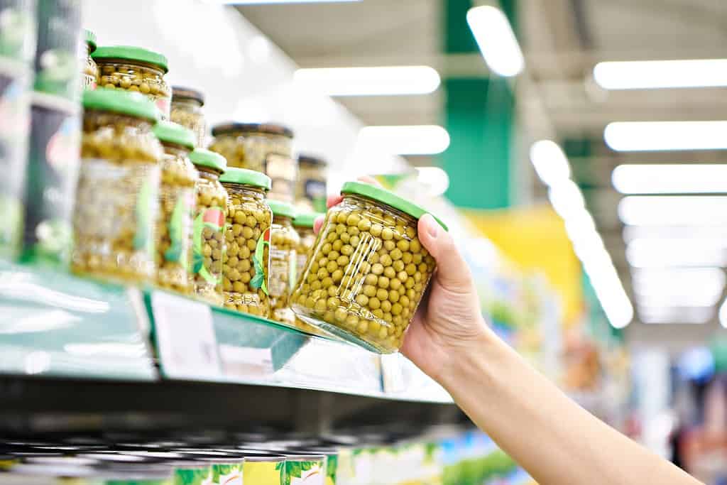 Green peas in a glass jar in the hands of a customer in a store
