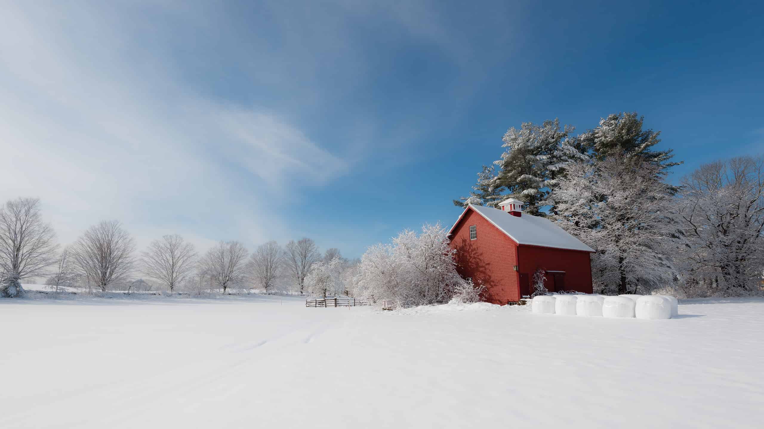 Winter in New England. Red farm building contrasting with white snow and blue sky. Ipswich, Massachusetts, USA