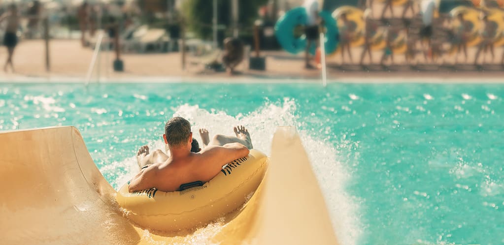 Person in an inner tube sliding down a water slide into a large pool area