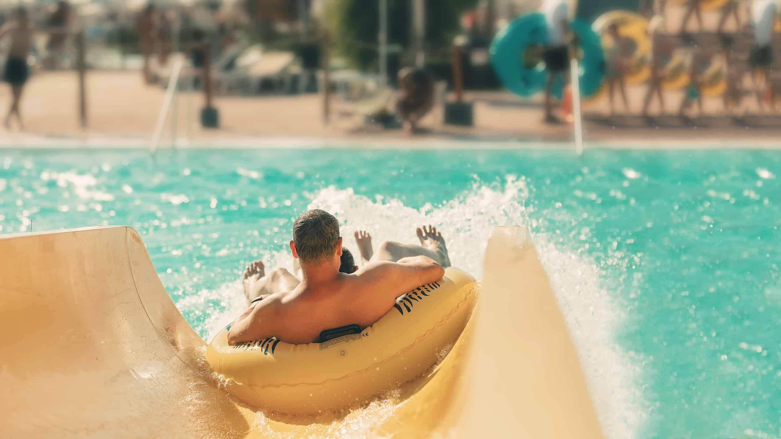 Person in an inner tube sliding down a water slide into a large pool area