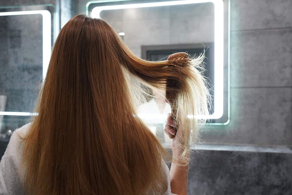 Woman in front of mirror brushing hair