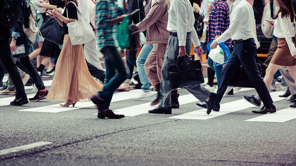 Group of people walking across a marked crosswalk on the street.