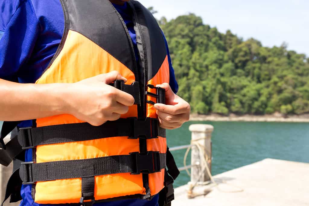 Young traveler wearing putting on a life jacket before get in the boat on vacation