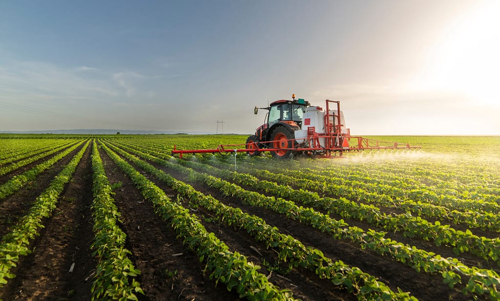 Tractor spraying pesticides on soy field with sprayer at spring