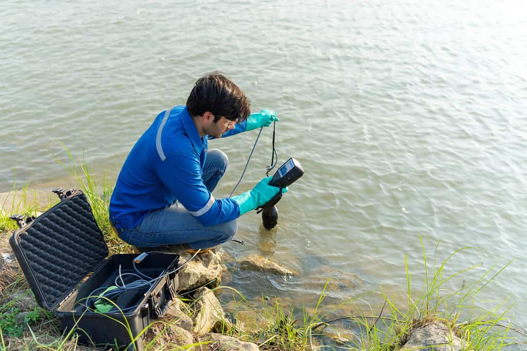A technician use the Professional Water Testing equipment to measure the water quality at the public canal. Portable multi parameter water quality measurement. Water quality monitoring concept.