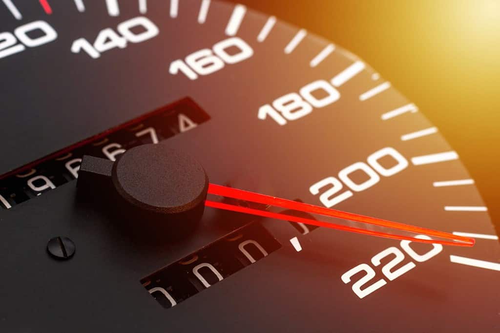 Car speedometer. Auto car speedometer shows 220 km h or miles.Closeup shot,dark black background.Automobile dangerous speed concept