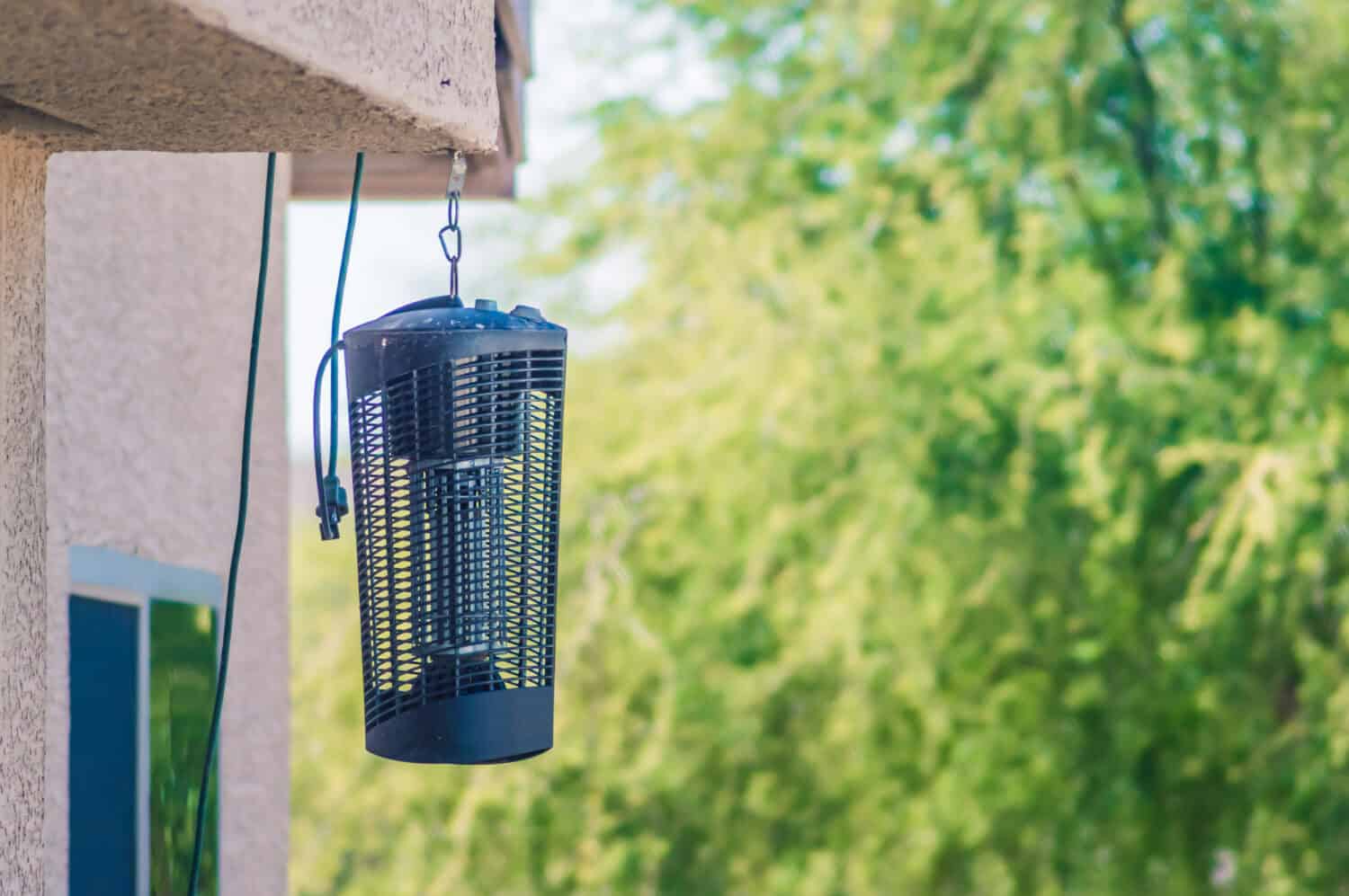 A large insect zapper hanging from a house in daylight