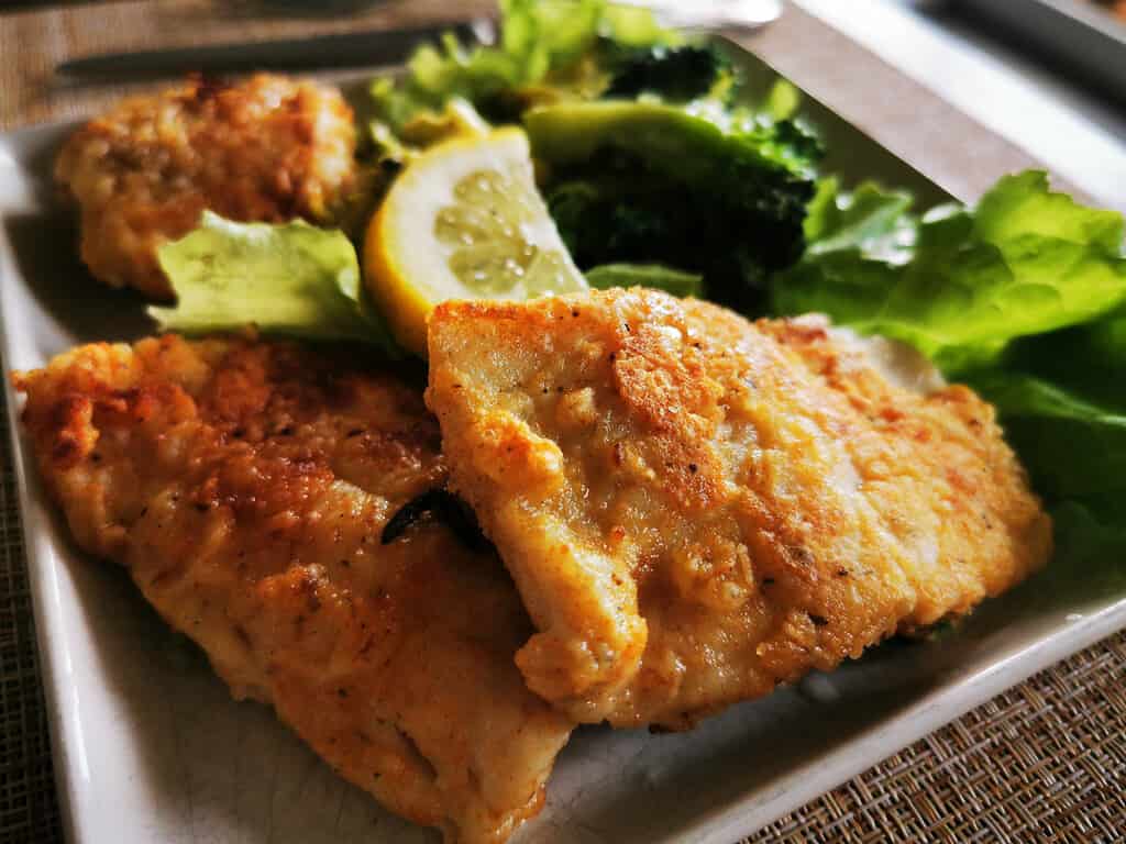 Fried fish. Breaded walleye fillet. Garnish with broccoli and green vegetables.