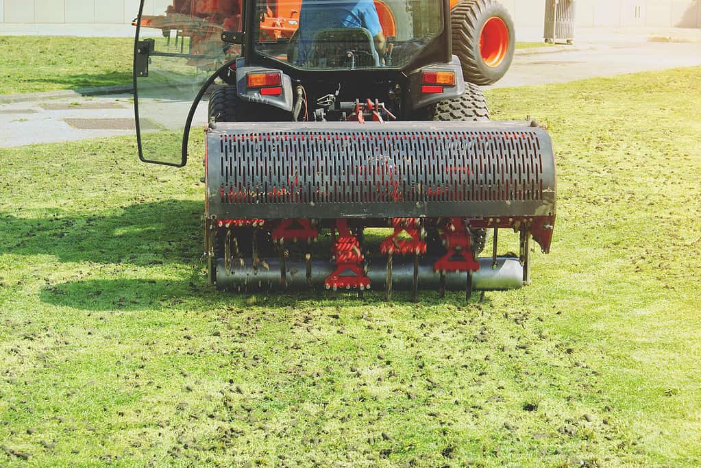 Gardener Operating Soil Aeration Machine on Grass Lawn