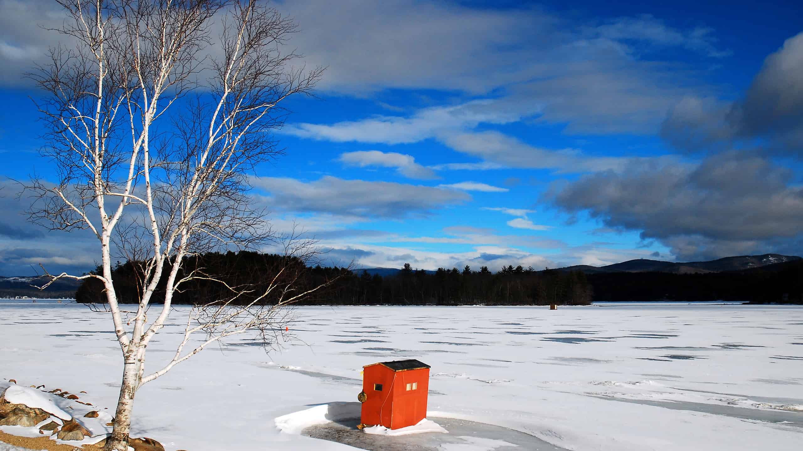 A lone, ice fishing shack stands on a frozen Newfound Lake in New England