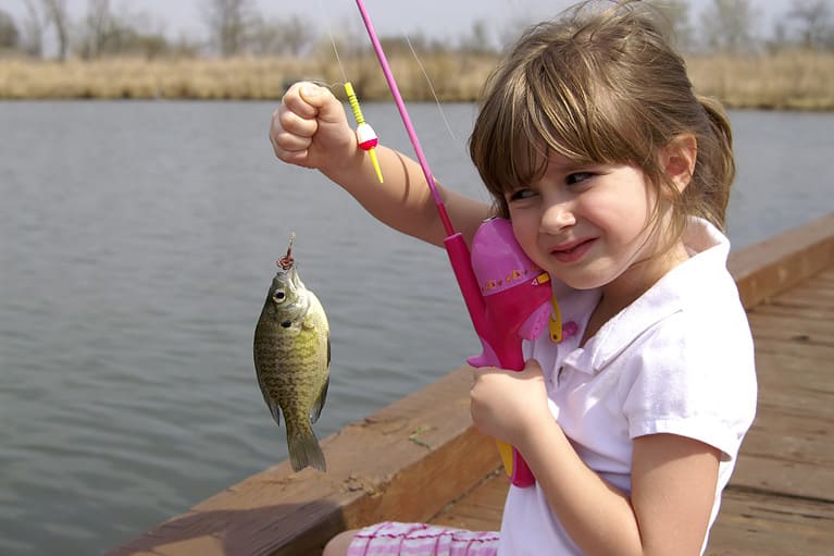 A young girl holding the fish she caught, bluegill