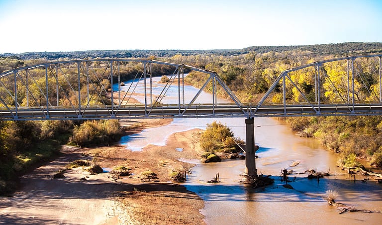 Bridge over the red river in central Texas. The Red River, or sometimes the Red River of the South, is a major tributary of the Mississippi
