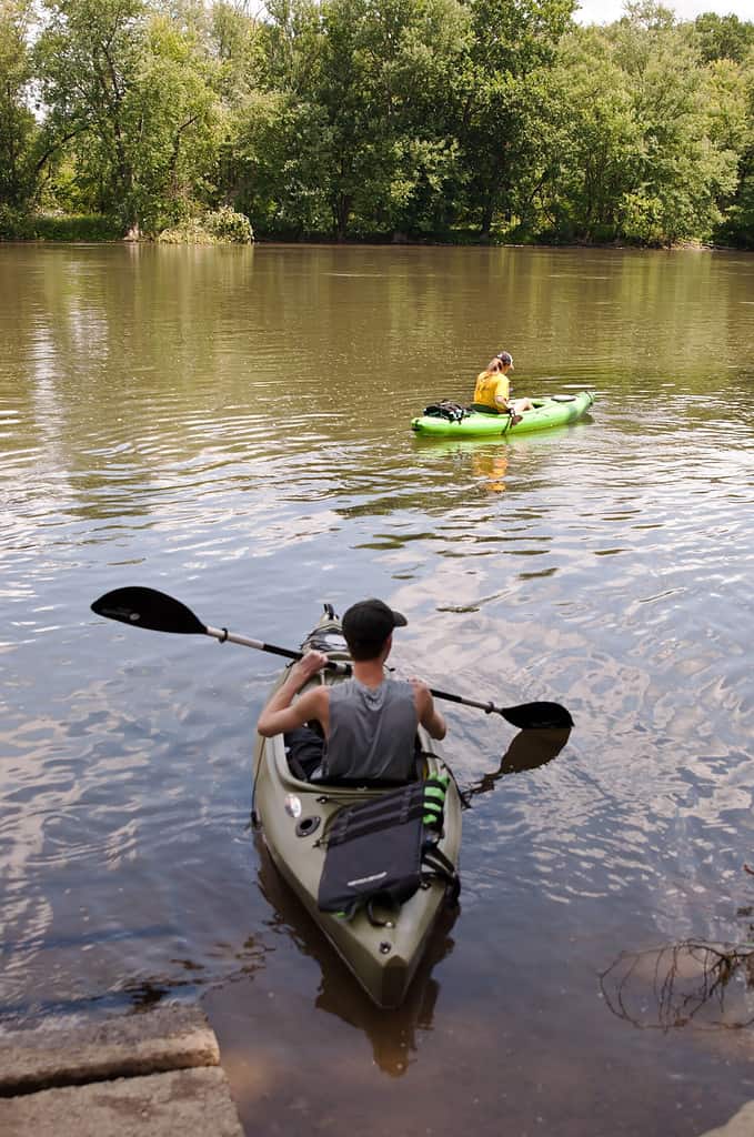 A man and woman in kayaks entering the Allegheny River in Warren county Pennsylvania, USA on a summer day