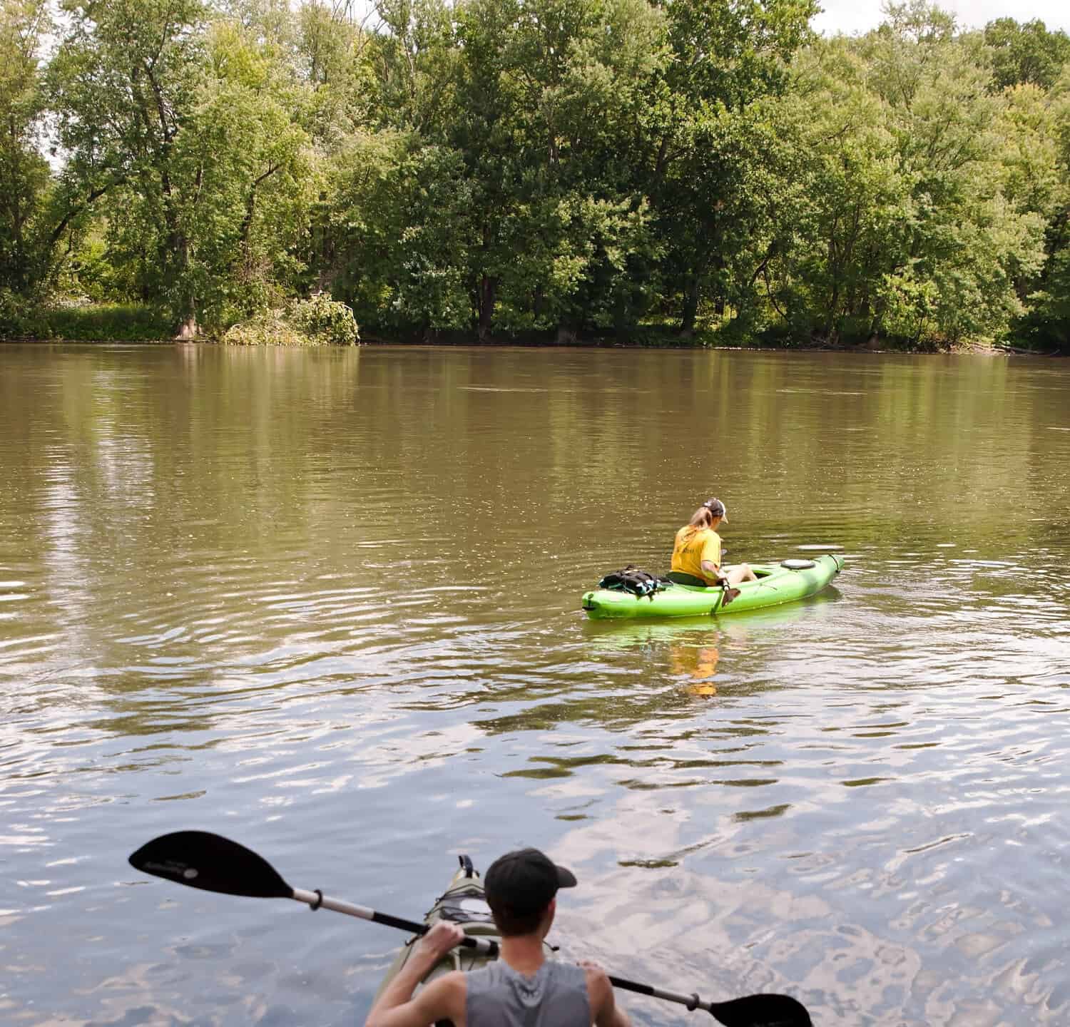 A man and woman in kayaks entering the Allegheny River in Warren county Pennsylvania, USA on a summer day