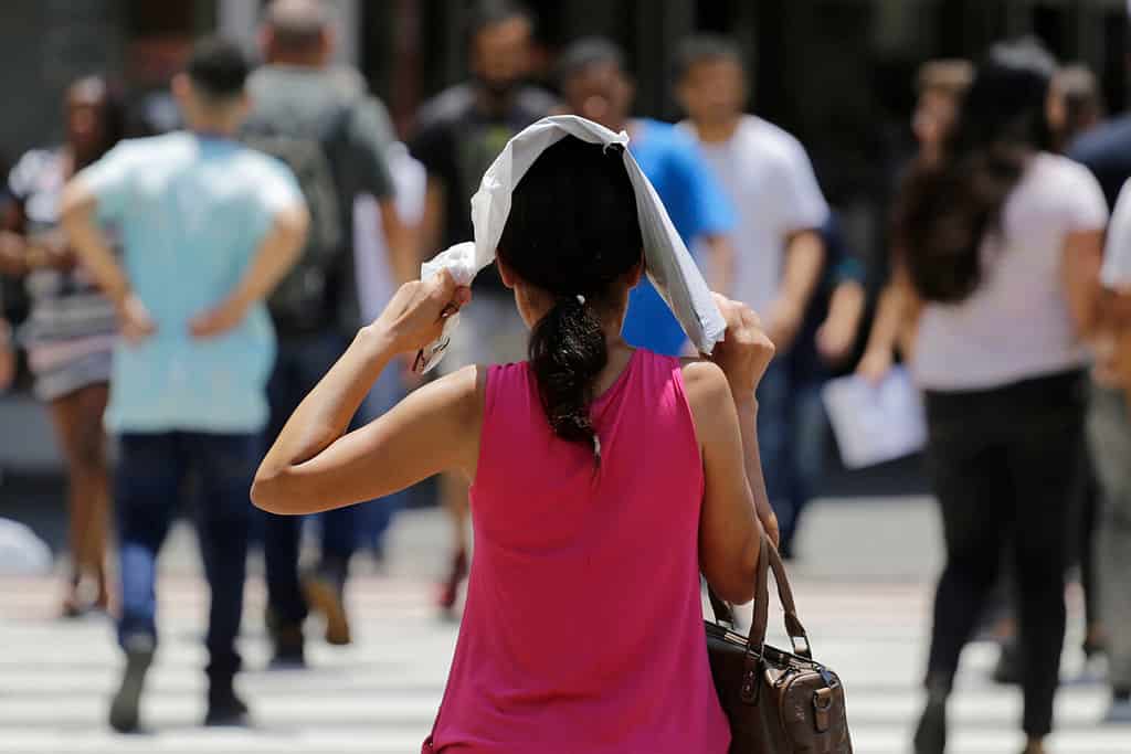 Woman protect herself from the hot sun while walks in a downtown street during an extreme heatwave in Sao Paulo, Brazil.
