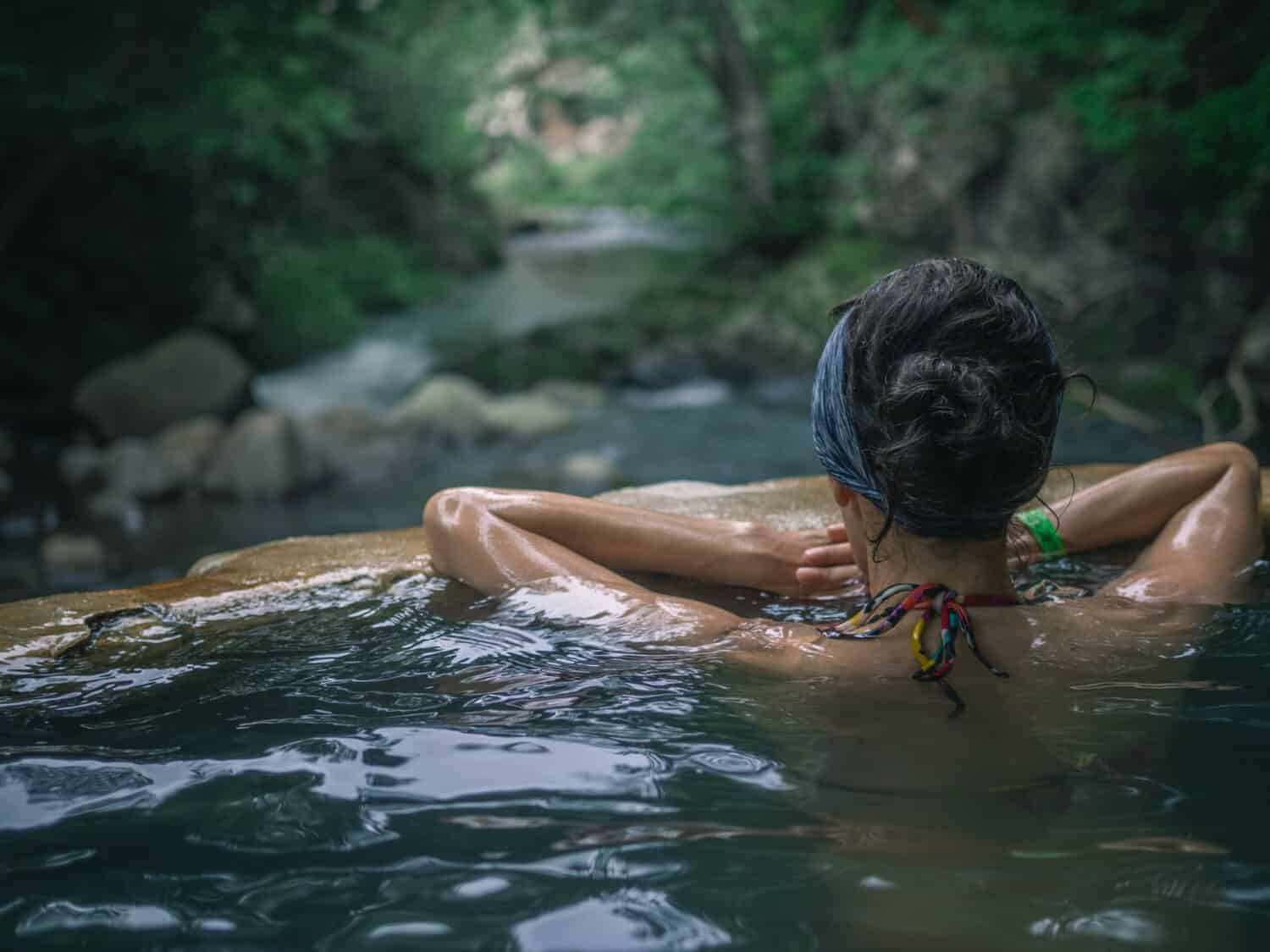 a woman sitting in a hot spring in the middle of jungle in Costa Rica