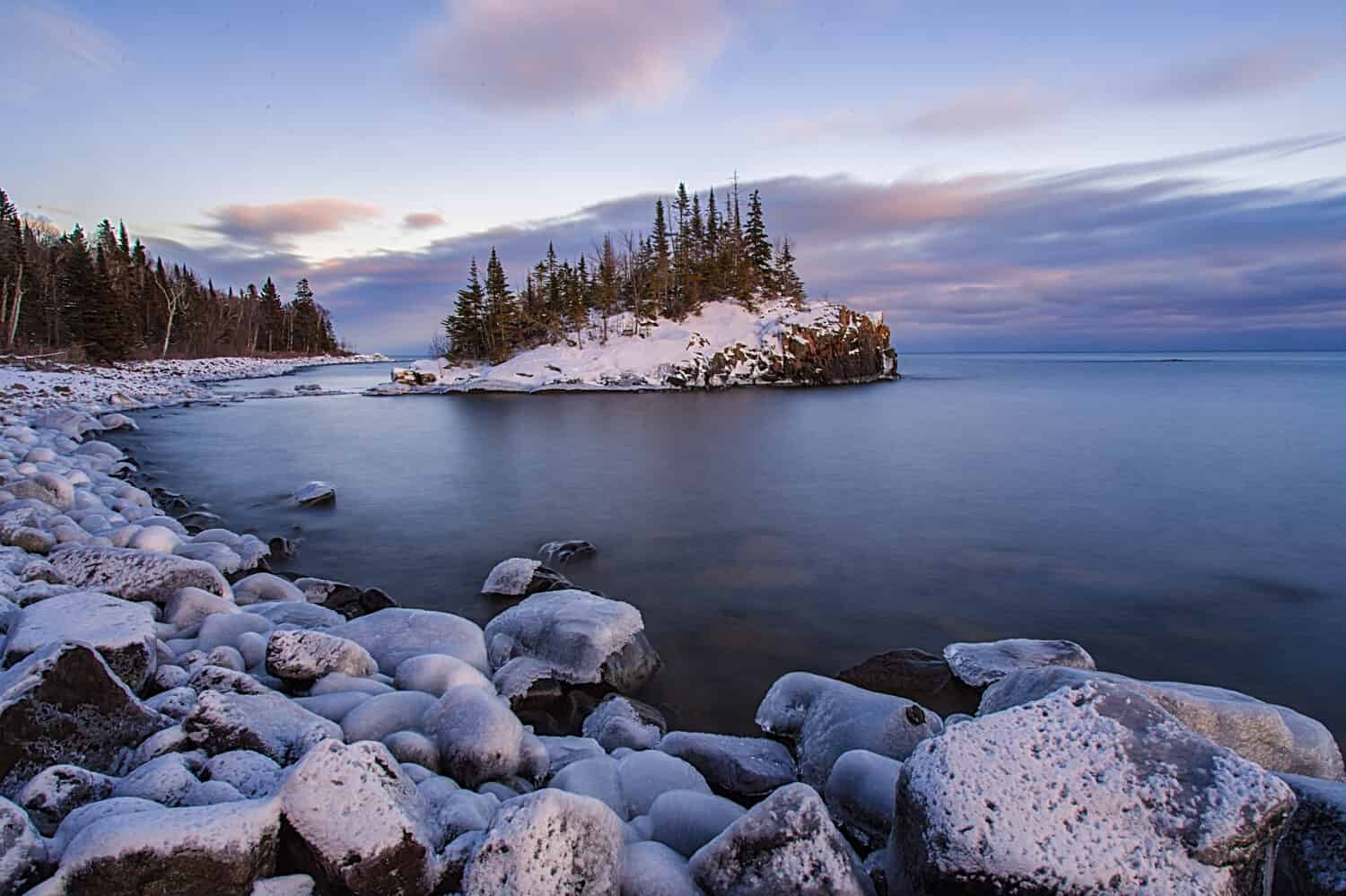 Snow covered island on Lake Superior during sunset.