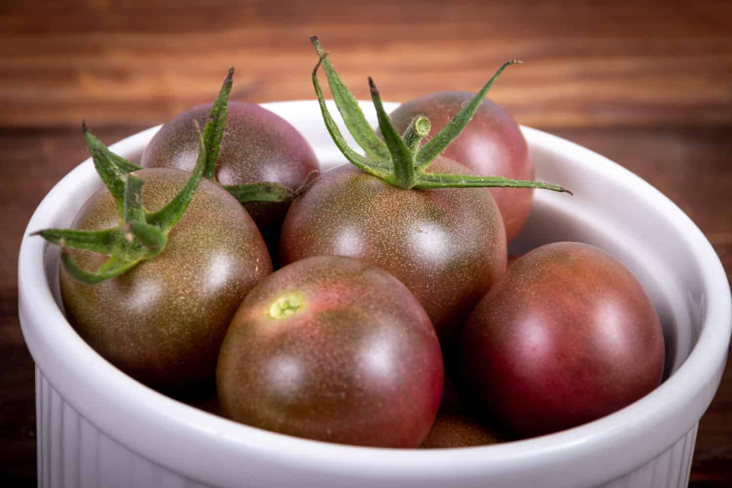 Harvested fresh black cherry cultivar cocktail size tomatoes on a bowl closeup