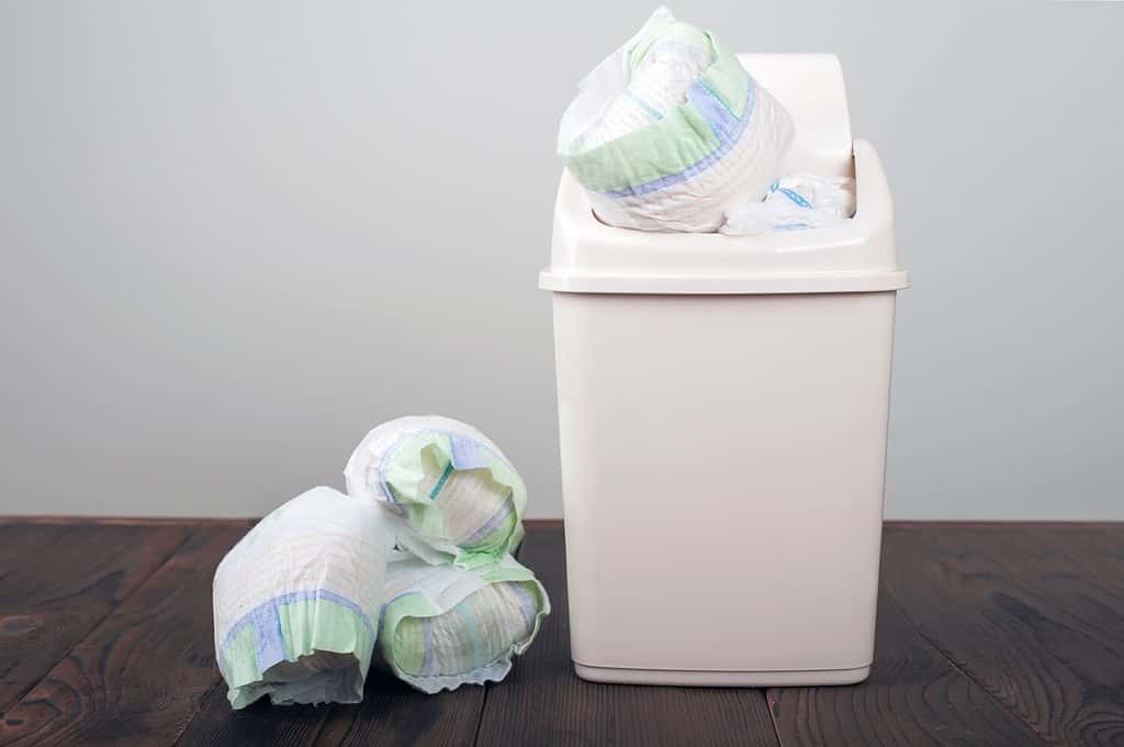 Diapers waste, dirty diapers in garbage pail Disposing of used baby nappies. Environmental Impact of Disposable Diapers. Pollution of the environment, soil and water