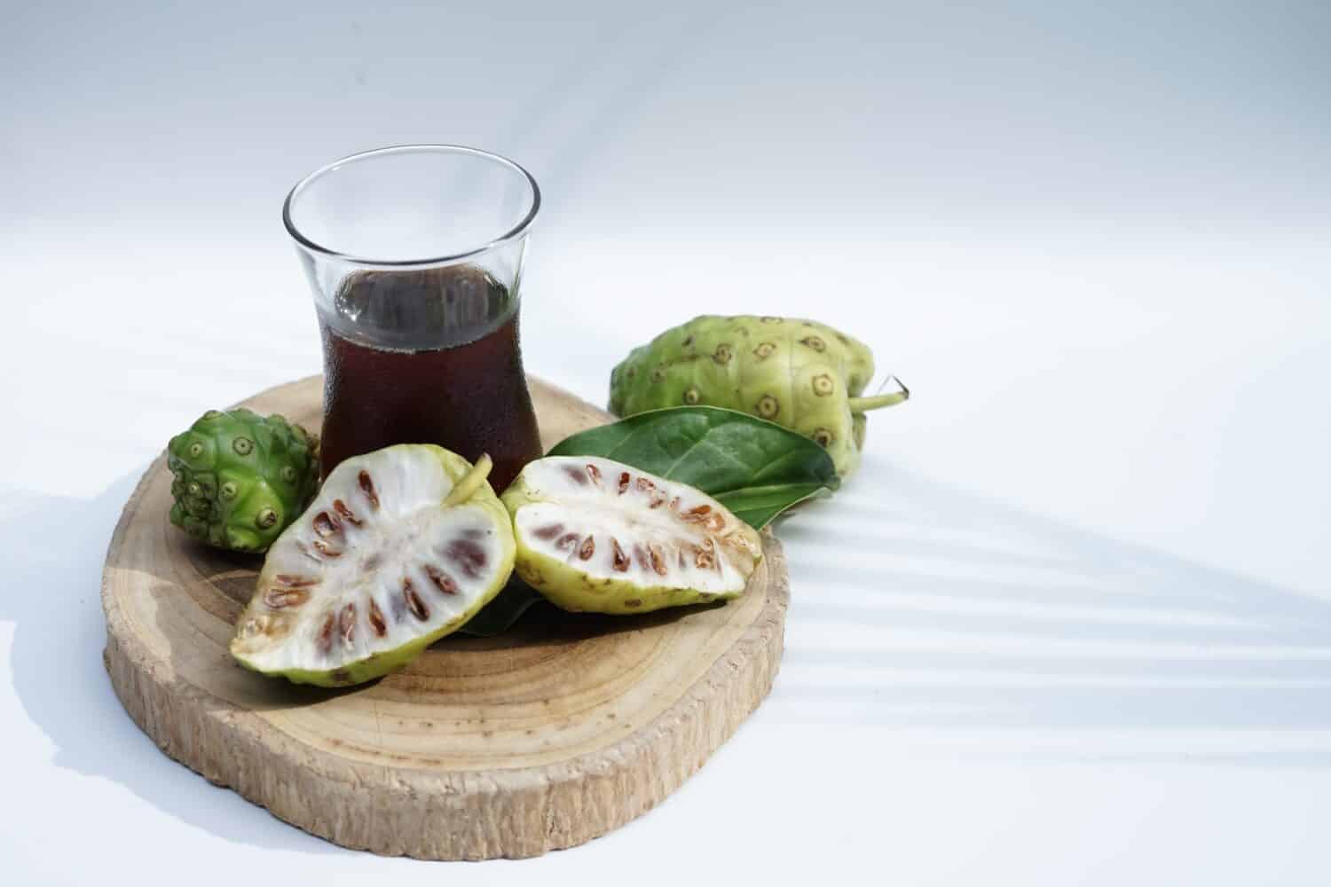 a glass of noni juice extracted and sliced on white background,selective focus