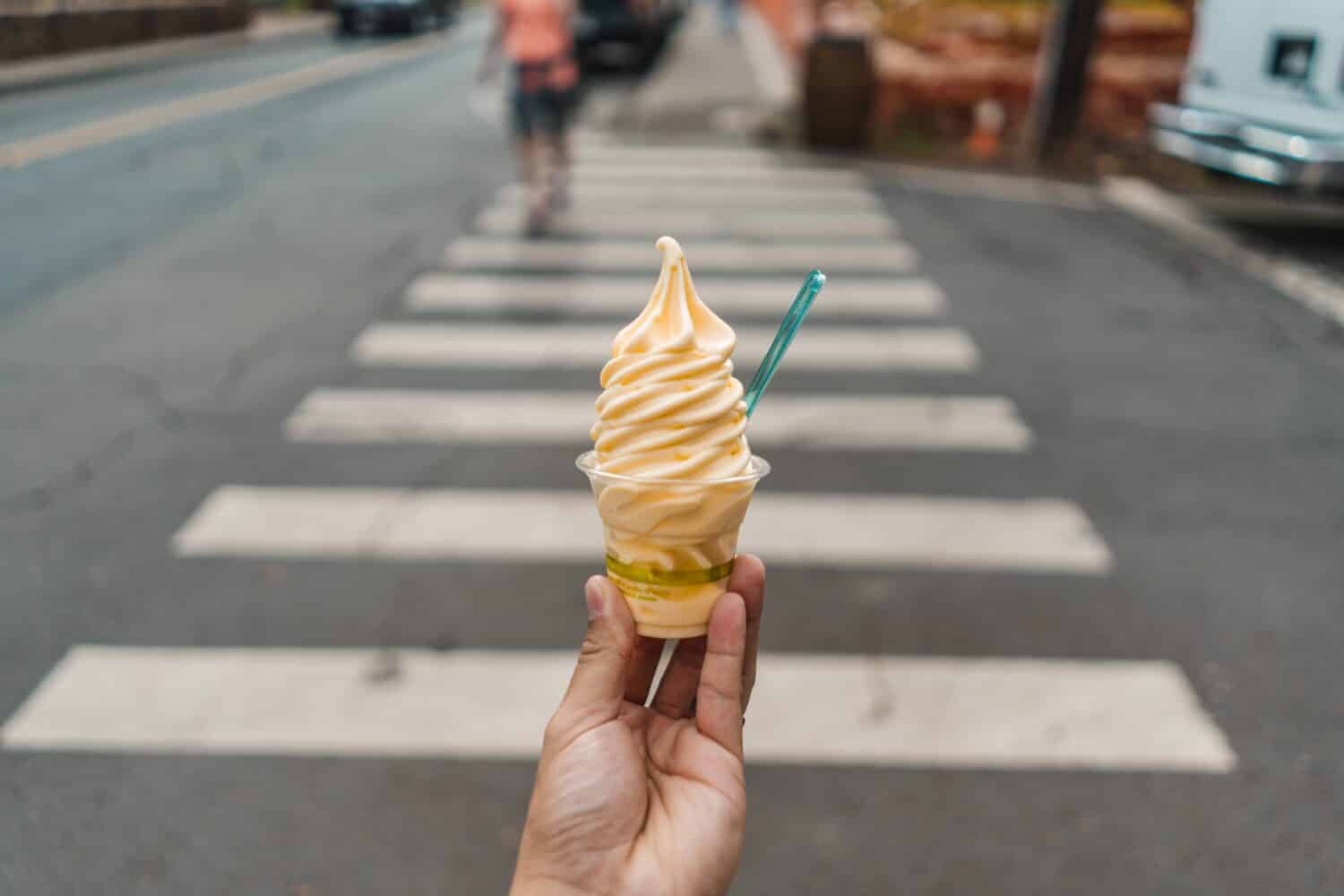 A Man Holding Pineapple Dole Whip Frozen Yogurt Ice Cream On Crosswalk Street