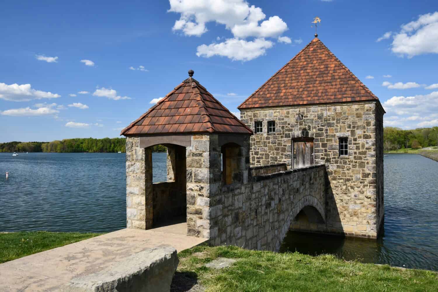 A scenic view of an old stone gate house on the water of Pymatuning Reservoir lake in USA