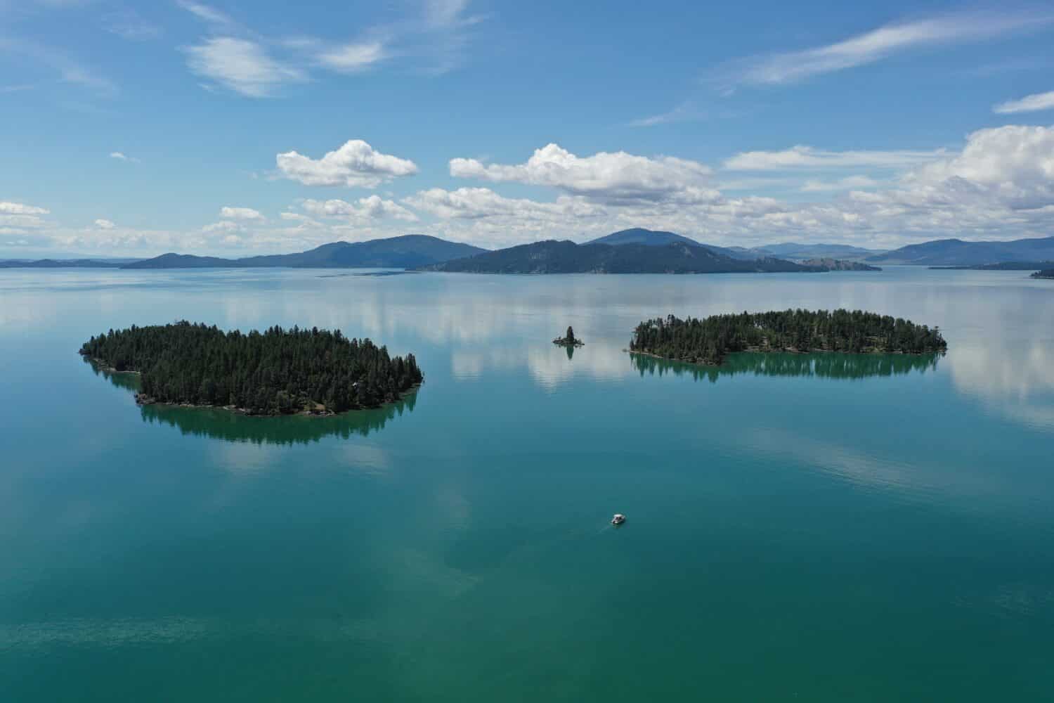 Aerial view of islands and distant mountains in Flathead Lake, Montana on calm summer morning.
