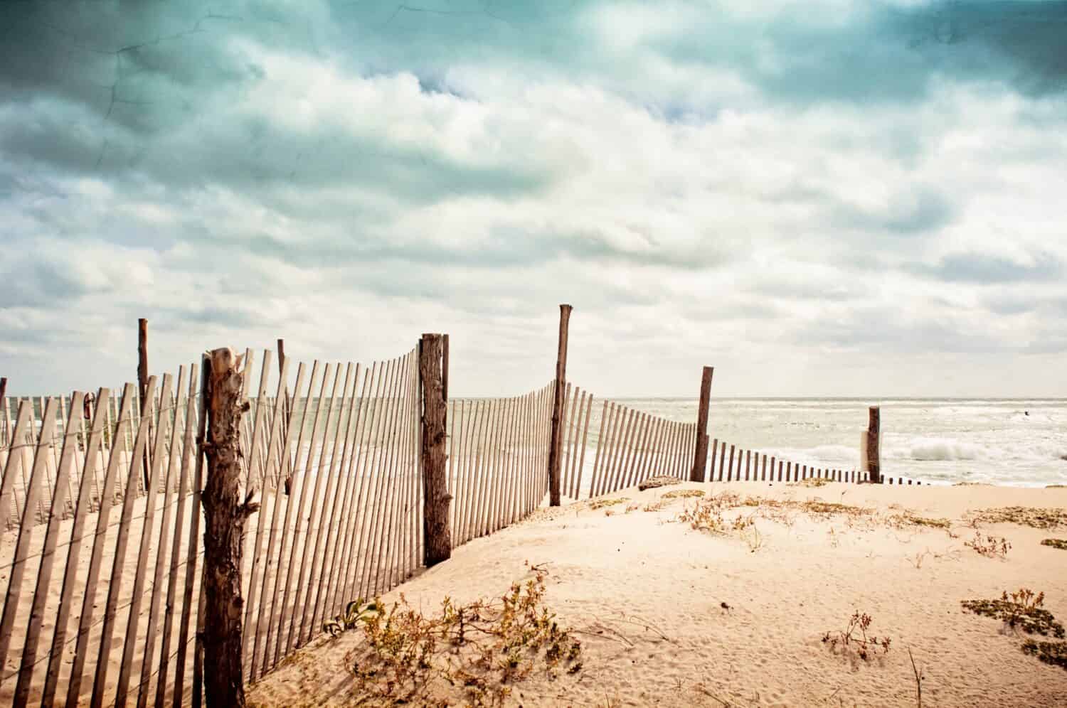 Beach scene on Long Beach Island, New Jersey.  Fence, dunes and moody sky.