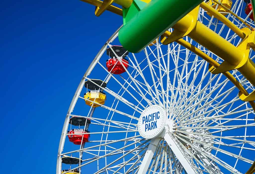 colorful ferris wheel in an amusement park on a clear day with blue sky background, pacific park, santa monica beach, los angeles, usa, november 2022