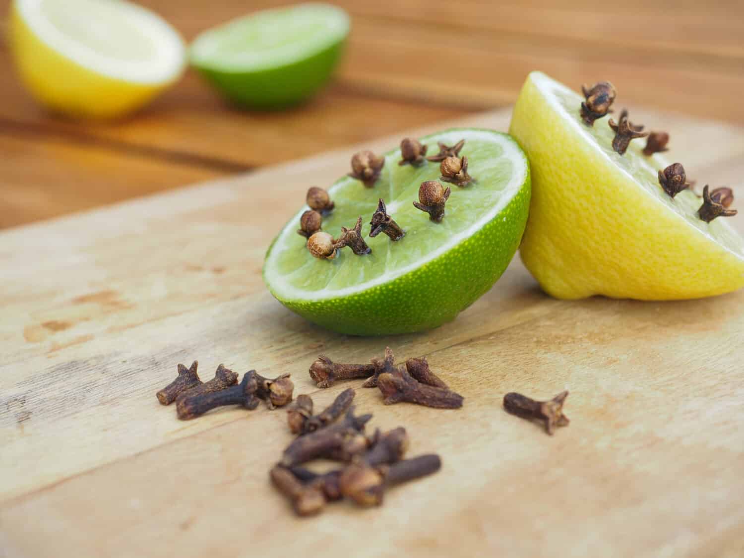 Natural homemade repellents on wooden table. Lime and lemon with cloves.