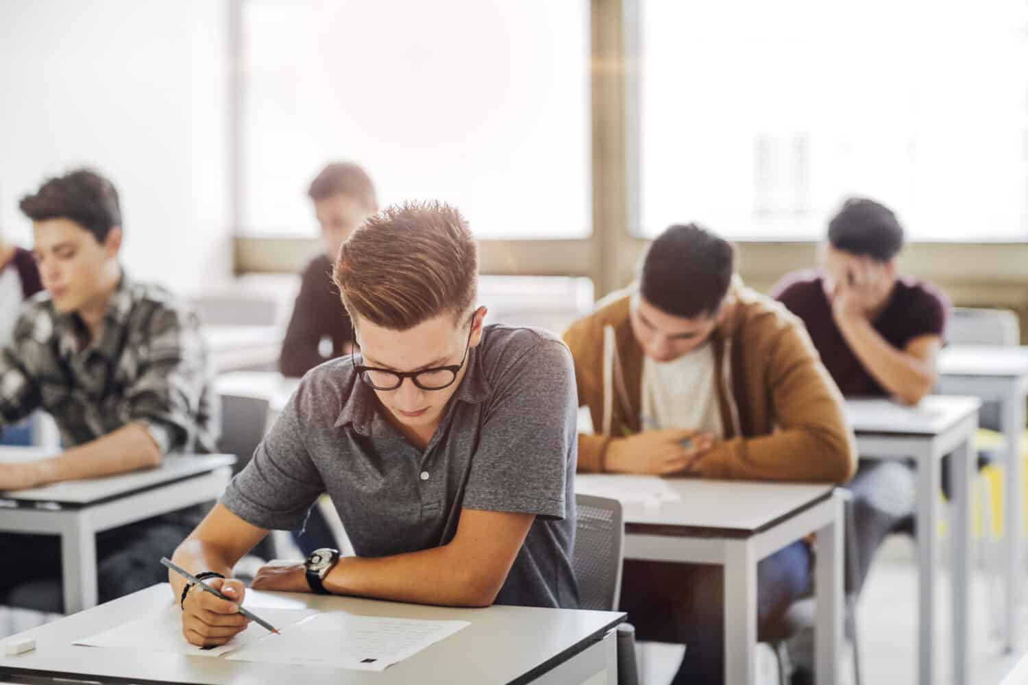 Group of high school students doing exam at classroom.