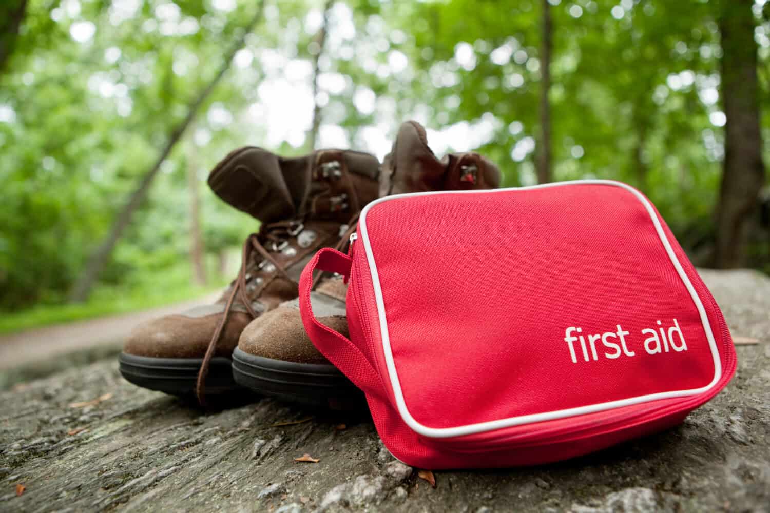 First aid kit and hiking boots in the woods