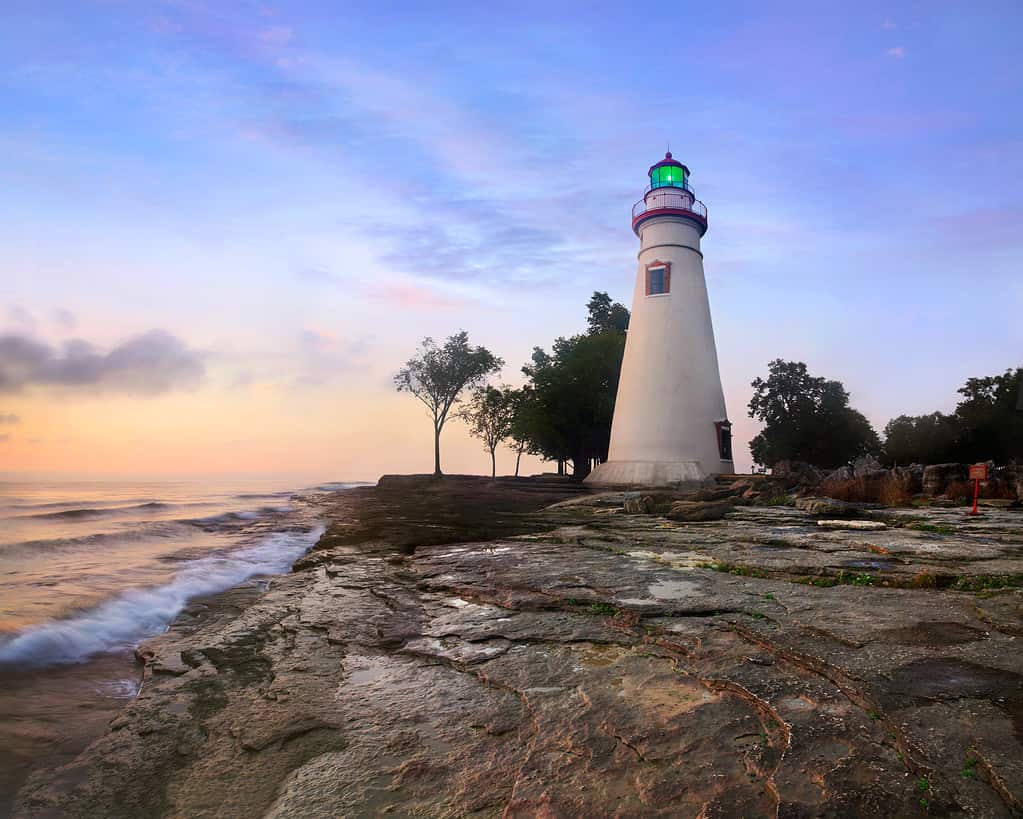 The Marblehead Lighthouse Bathed In The First Light Of Dawn On A Foggy Morning Over Lake Erie At Marblehead Ohio, USA