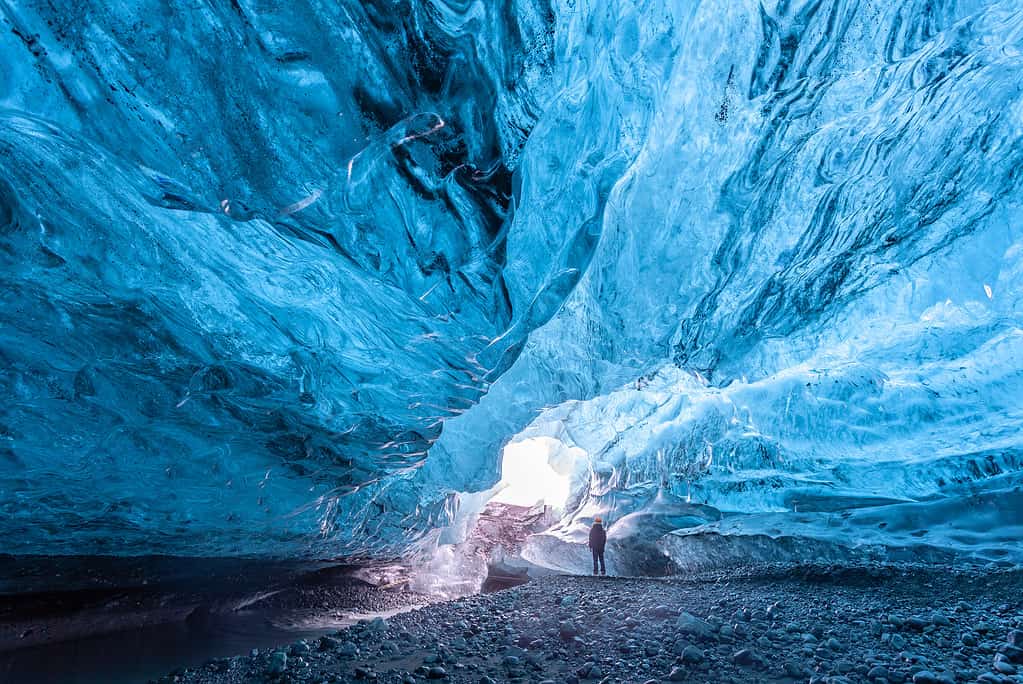 Tourist standing in an ice cave in Vatnajökull glacier Iceland
