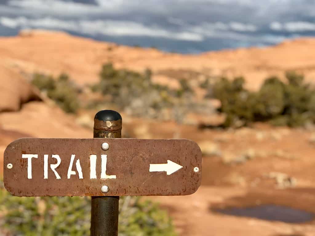 Metal trail sign with blurred sandstone background in Arches national park