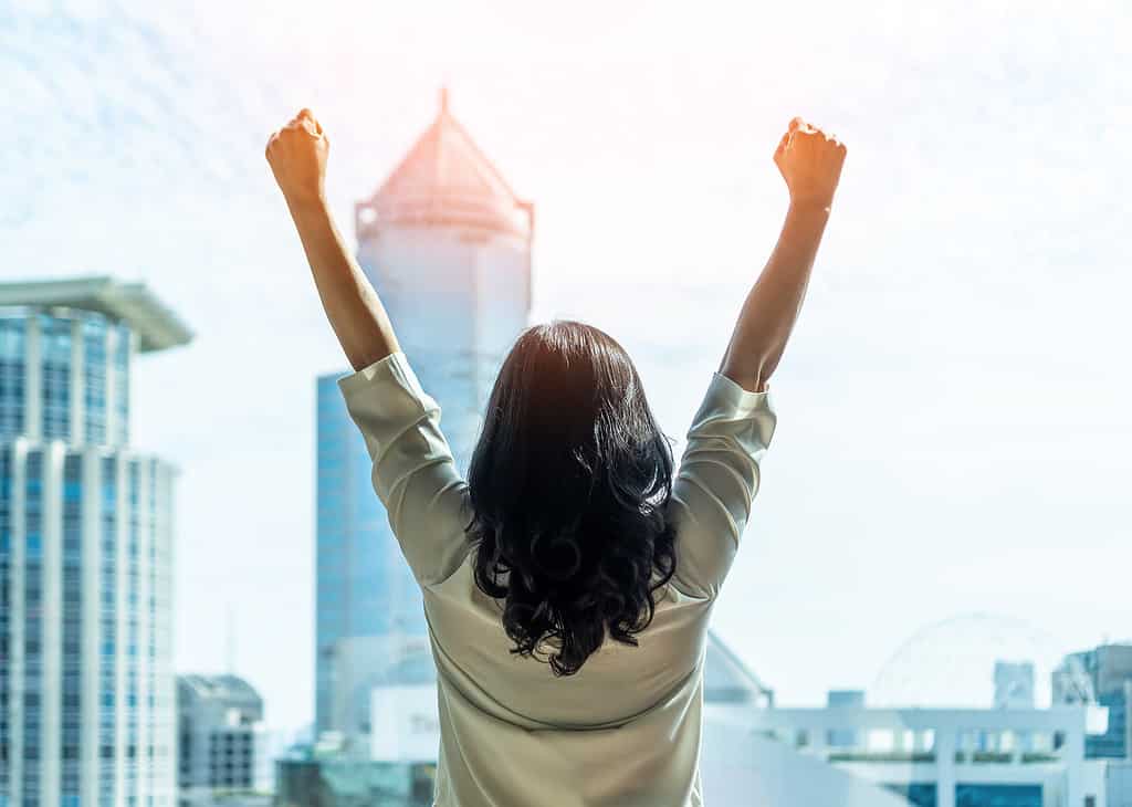  Lady raising her arms up celebrating.