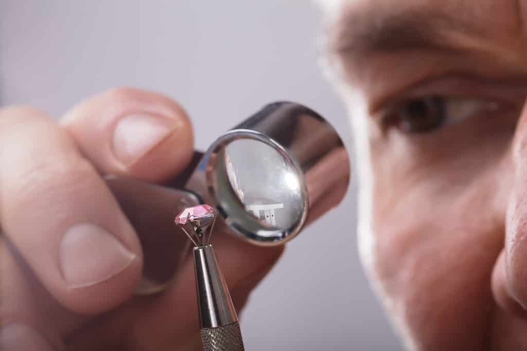 Close-up Of A Person's Hand Checking Diamond Through Magnifying Loupe