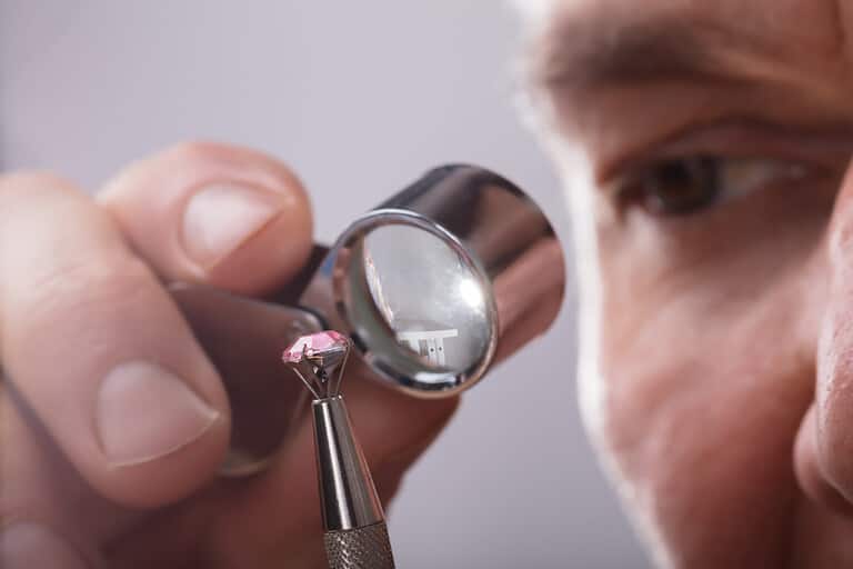 Close-up Of A Person's Hand Checking Diamond Through Magnifying Loupe