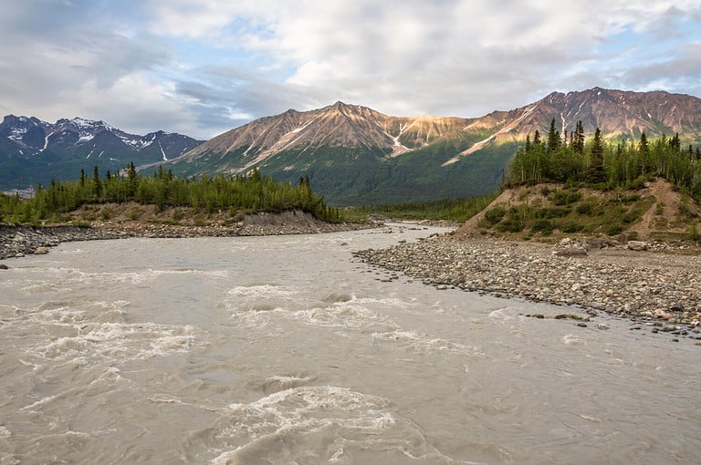 Looking upstream on the Chitina River from the McCarthy foot bridge towards the historic Kennecott mine on a cool summer evening. Wrangell St. Elias National Park, Alaska.