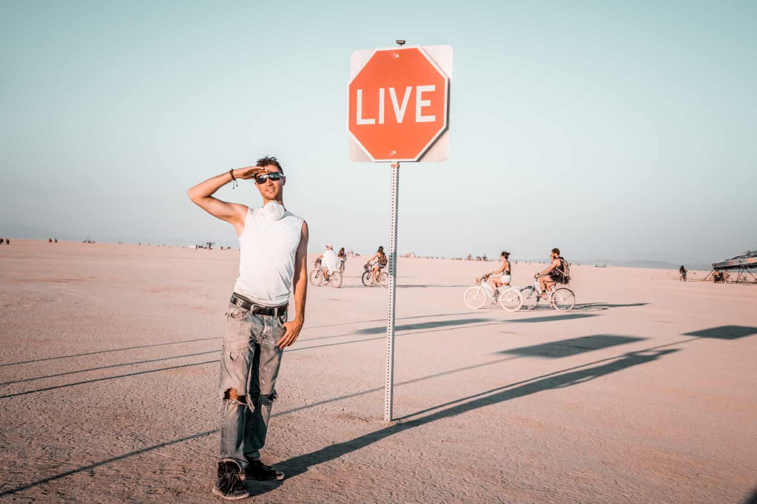 Young man standing by the dream sign in the middle of a desert at the Burning Man art festival. Sign to live your life.