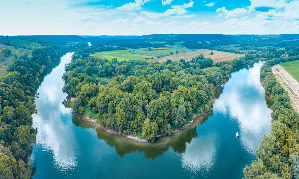 Aerial view panorama of lush forestry and the bending Kentucky River with a boat on the water and cloud reflections in the sky