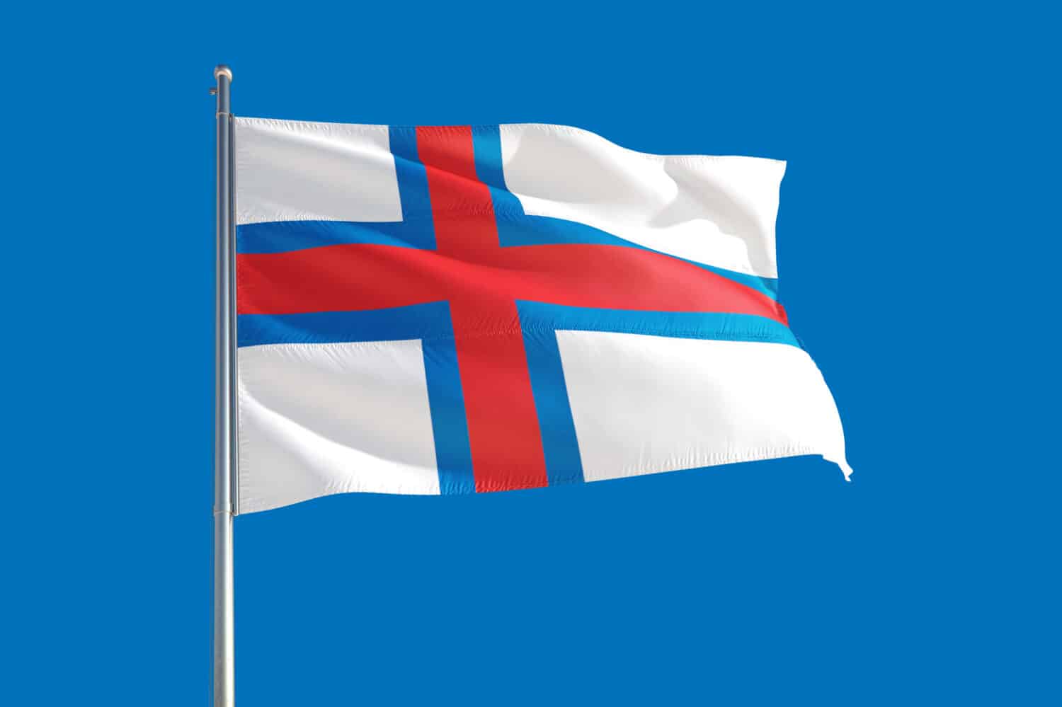 Faroe Islands national flag waving in the wind on a deep blue sky. High quality fabric. International relations concept.