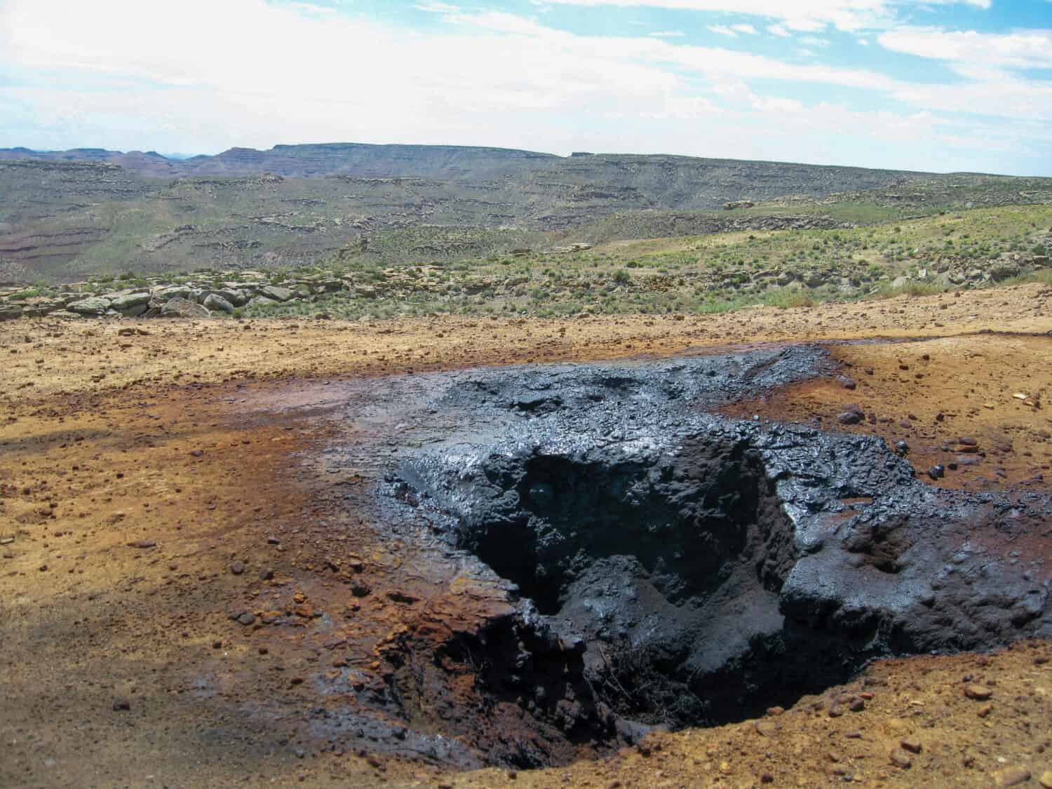 A fuming ground fissure vents noxious gas from an underground coal seam fire on Smoky Mountain, UT. The gas leaves black petroleum deposits around the vent.