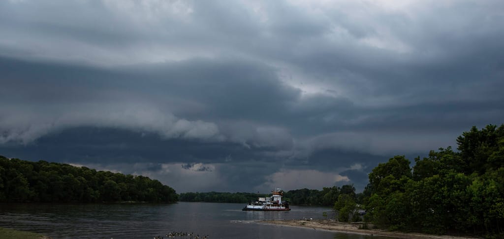 Large shelf cloud blowing in over the Tombigbee River with a barge in view.