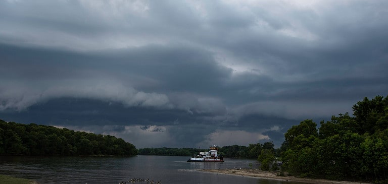 Large shelf cloud blowing in over the Tombigbee River with a barge in view.