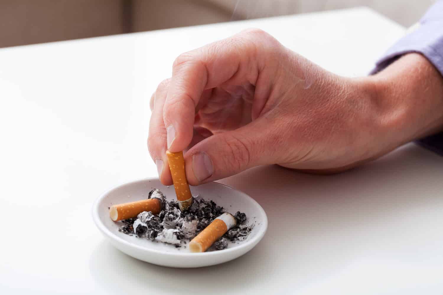 Hand putting the cigarette on an ashtray